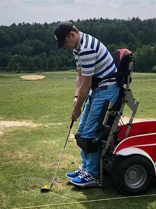 Mensch mit Behinderung beim Golfen im E-Rollstuhl im aufgestelltem Zustand (stehend)