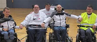 E-Rollstuhlfussball Team. 4 E-Rollifahrer mit einem Trainer