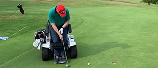 Rollstuhlfahrer in einem speziellen Goldrollstuhl beim Golfen